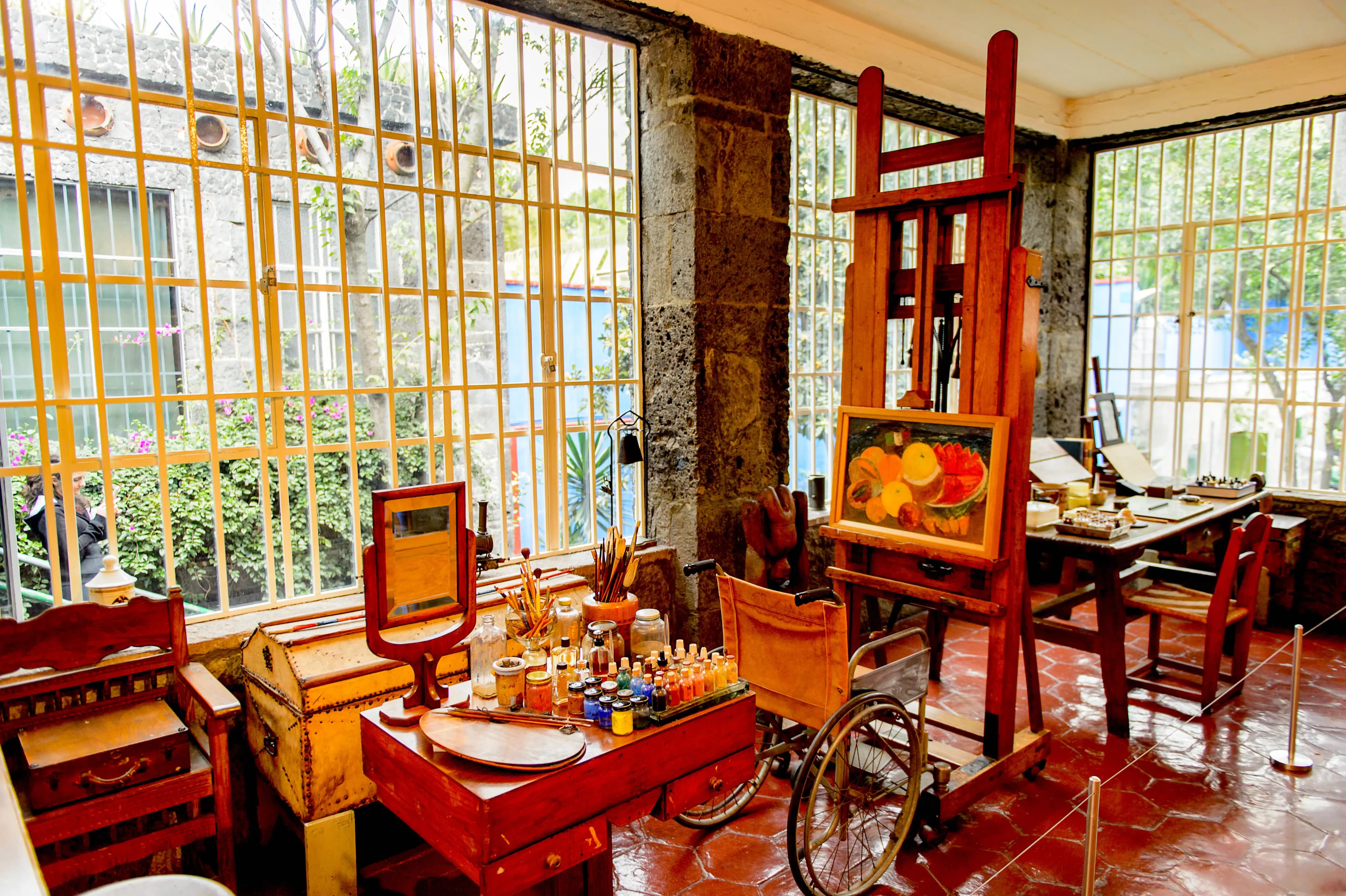 A vivid blue Casa Azul passageway surrounded by plants and warm red trim